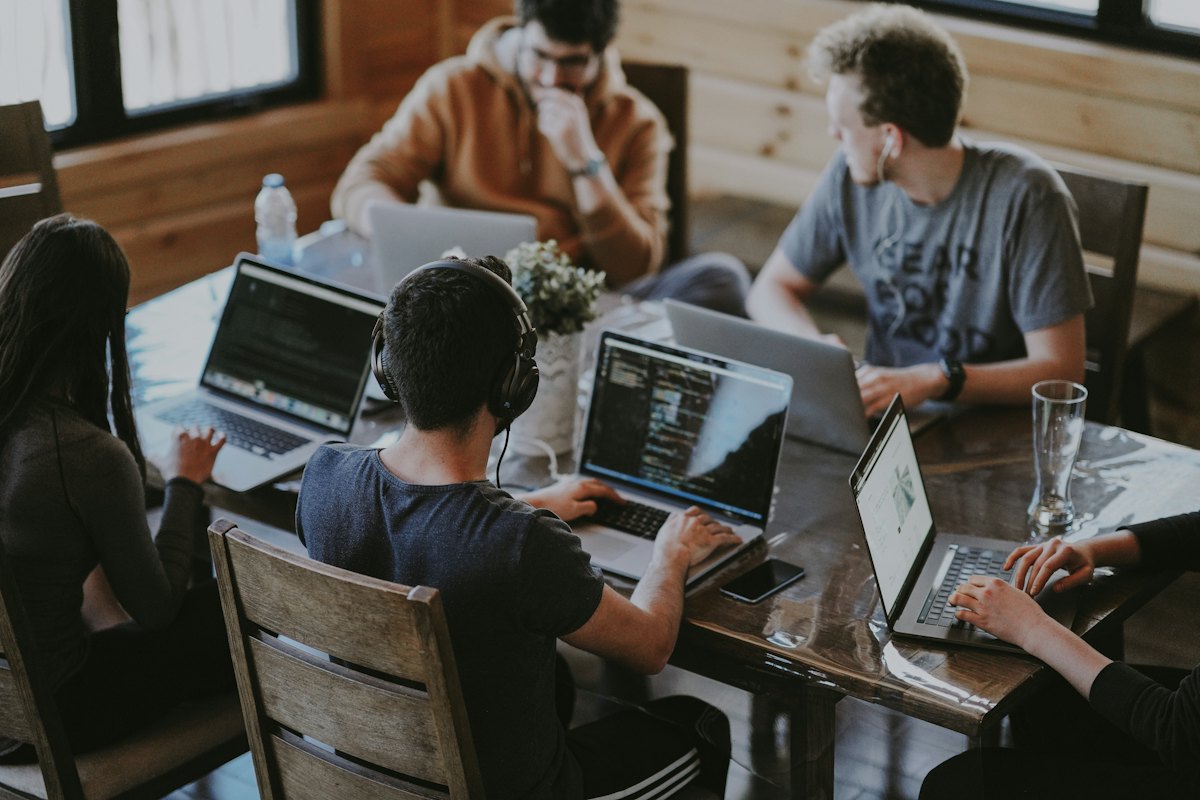 Engineers collaborating around a table with laptops